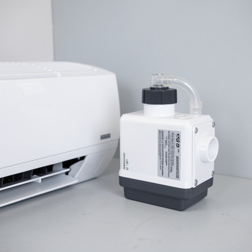 Pompe de relevage compacte pour condensats de climatisation, avec boîtier blanc et gris et tuyau translucide.